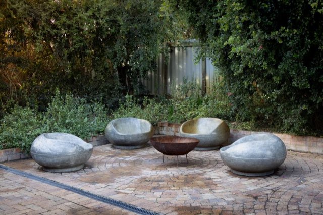 Sculptural stone seats around a fire bowl on a paver court
