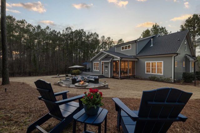 Adirondack chairs around a fire pit behind a modern home