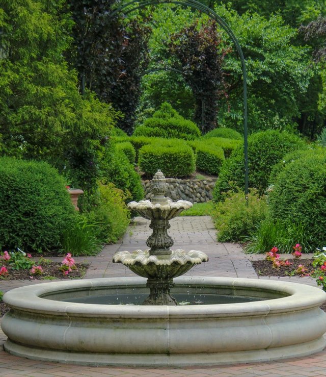Formal garden with a tiered stone fountain and clipped hedges