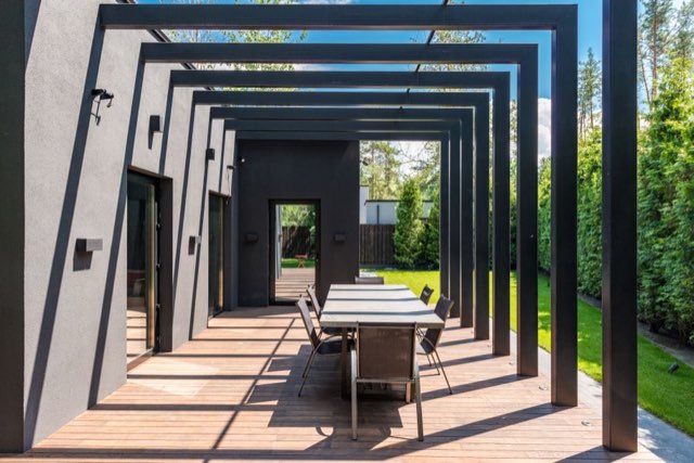 Modern black pergola corridor over an outdoor dining table